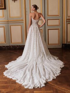 a woman in a white wedding dress standing on a wooden floor with her back to the camera