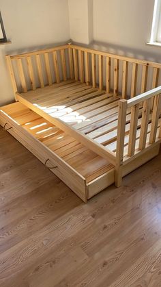 a wooden bed frame sitting on top of a hard wood floor next to a window