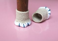 a crocheted slipper is sitting next to a wooden pole on a pink surface