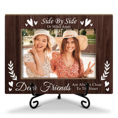 two girls with hats on their heads are smiling and posing in front of a wooden frame that says, side by side or miles apart