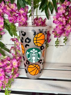 the starbucks cup has been decorated with basketballs and leopard print, along with pink flowers