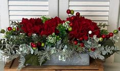 a bouquet of red roses and greenery in a metal container