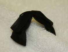 a black piece of cloth on top of a white blanket with a knoted edge