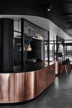 the interior of a modern restaurant with black and copper accents on the countertop, along with wooden stools