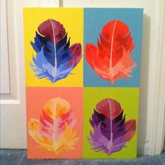 four different colored feathers painted on canvases in front of a white door with blue carpet