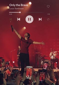 a man standing on top of a stage with his arms in the air and hands up