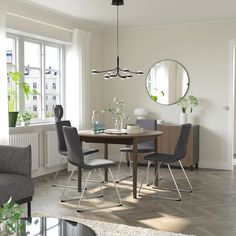 a dining room table with four chairs and a round mirror on the wall above it