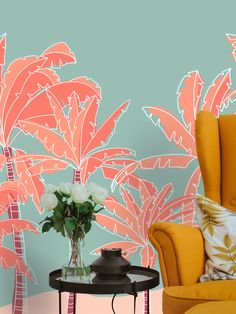 an orange chair sitting in front of a wall with palm trees and flowers on it