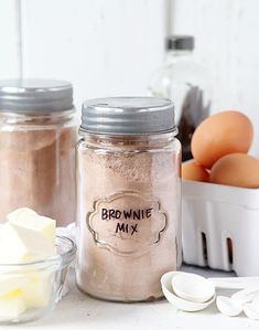 two mason jars filled with brownie mix next to eggs