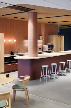 an open kitchen with bar stools in the center and wooden cabinets on the other side