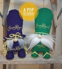 two green and purple gnomes sitting on top of a wooden shelf