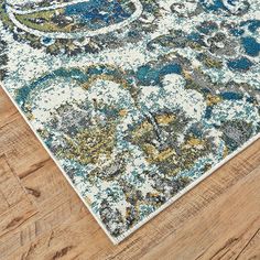 an area rug with blue, green and yellow colors on the floor in a living room