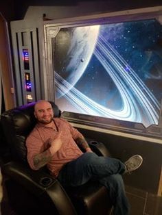 a man sitting in a chair with his feet up on the ground next to a window