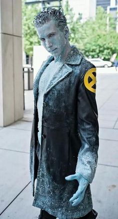 a man with blue paint on his face and hands standing in front of a building