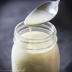 a spoon is pouring milk into a jar