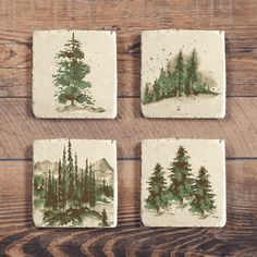 four coasters with trees painted on them sitting on a wooden table next to each other