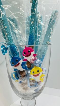 a clear glass vase filled with toothbrushes and little sharks in it's wrappers