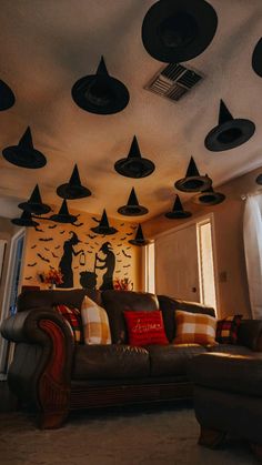 a living room filled with furniture and lots of black hats hanging from the ceiling above