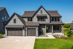 a large gray house with two garages on the front and one car door open