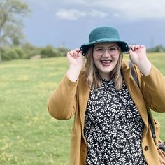 a woman wearing a hat standing in a field