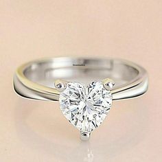 a heart shaped diamond ring on a white surface