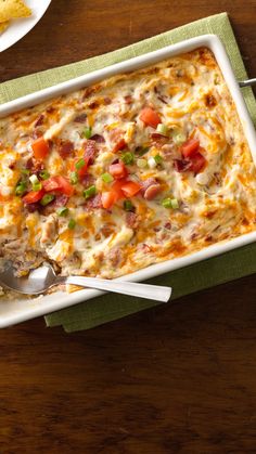 a casserole dish with meat and vegetables in it on a green napkin next to some bread