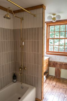 a bath tub sitting inside of a bathroom next to a wooden floored wall and window