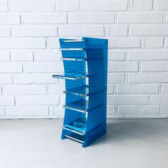 a blue shelf stands against a white brick wall