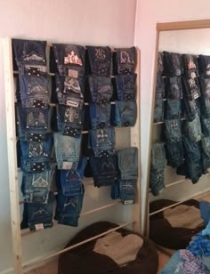 there are many pairs of blue jeans hanging on the wall in this room with mirrors