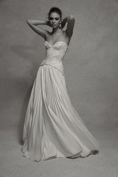 black and white photo of woman in dress posing for the camera with her hands behind her head