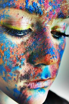 a woman's face is covered in multicolored powder