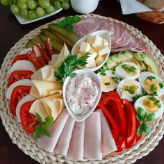 an assortment of meats and cheeses on a platter next to grapes, bread