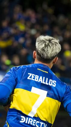 a soccer player in blue and yellow uniform with his back turned to the camera,