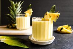 two glasses filled with pineapple smoothie on top of a table