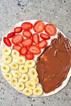 a plate topped with sliced bananas and strawberries next to a chocolate frosted dessert