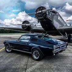 an old car is parked in front of a plane