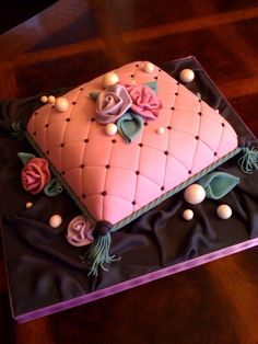 a cake with pink frosting and flowers on it sitting on top of a table