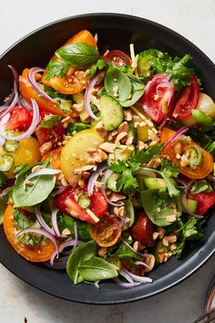 a salad in a black bowl with tomatoes, onions and spinach on the side