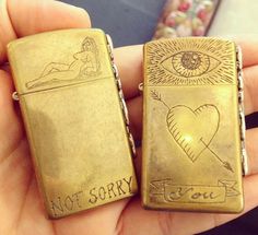 someone is holding two lighters that say not sorry and i love you with an all seeing eye on them