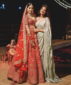 two women dressed in red and green outfits posing for the camera with lights behind them