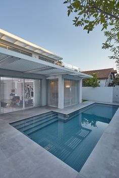 an empty swimming pool in front of a modern house