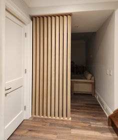 an open door leading to a bedroom with a bed in the corner and wooden slats on the wall