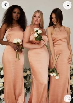 three women in long dresses standing next to each other with flowers on their laps and one woman holding a bouquet