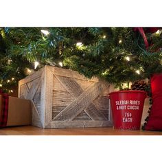 a christmas tree with presents under it and a wooden box on the floor next to it