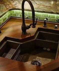 a kitchen sink sitting under a faucet next to a green tiled counter top