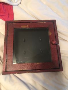 an old wooden frame with holes in it on a white sheeted bed, next to a pair of shoes