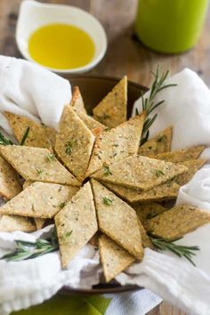 crackers are arranged in a bowl on a table next to a cup of olive oil