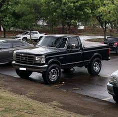 several trucks parked in a parking lot with trees in the backgroung area