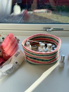 a knitted basket sitting on top of a window sill next to sewing supplies