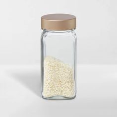 a glass jar filled with rice on top of a white table next to a brown lid